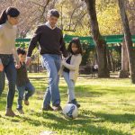 A family plays soccer together in a sunny park, enjoying quality time outdoors.
