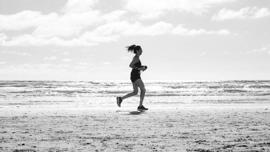 A woman jogging on La Lucila del Mar beach, Argentina in a monochrome setting. Capturing fitness and freedom.