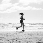 A woman jogging on La Lucila del Mar beach, Argentina in a monochrome setting. Capturing fitness and freedom.